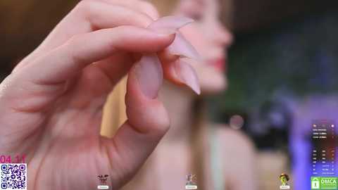 A close-up video shows a fair-skinned hand holding a piece of raw fish, with a blurred background featuring a blurred face and an iPad displaying a QR code and app icons.