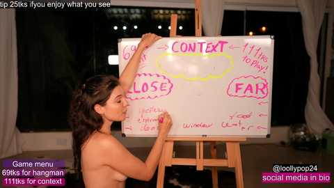 Media: Video of a nude woman writing \"CONTENT\" on a whiteboard in a dimly lit room, with text overlays about social media, hashtags, and her name.
