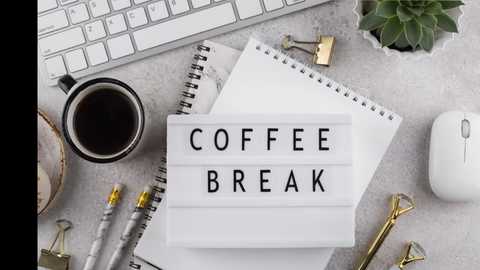 Media: Video of a minimalist desk setup featuring a black coffee cup, a silver pen, a white mouse, a small plant, and a sign reading \"COFFEE BREAK\" on a white spiral notebook, all on a light grey surface.