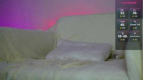 Video of a dimly lit, minimalist room with a white couch and a plush white blanket, featuring a video game interface on the right displaying health, stamina, and ammo bars.