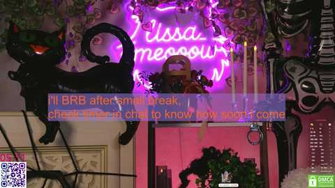 Media: Video of a vibrant, gothic-themed room with a neon \"Isla mesa\" sign, black cat sculpture, and spooky decor; text overlay mentions a BRR after small break.
