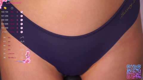 Video of a close-up of a woman's lower torso in navy blue panties with a small pink floral design. The background includes a virtual fitness app screen with statistics and motivational phrases.