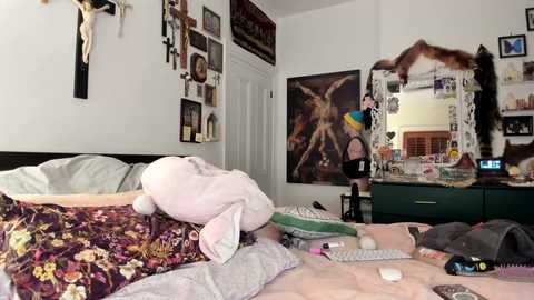 Media: Video of a messy bedroom with a large bed, stuffed animal, a framed photo of a woman, and a cluttered desk.