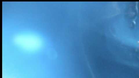 A video captures a bright, glowing blue orb in a cloud-filled sky, with a soft, hazy texture and blurred details, creating a serene and mysterious atmosphere.