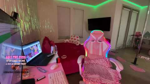 Video of a messy, pink-themed gaming room with a rainbow-lit chair, computer monitor, and scattered papers.