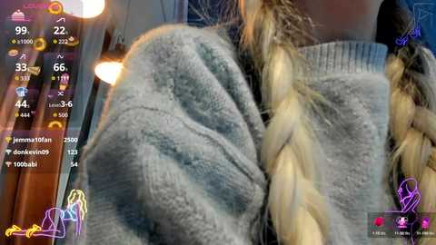 Media: Video of a woman's back in a cozy, knit sweater with braided hair. Background shows a dimly lit room with a wall-mounted lamp and a colorful social media interface.