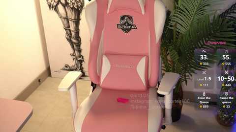 Video of a pink and white gaming chair with a \"Valorant\" logo, against a wall with a black and white graffiti mural, and a green plant on the right.