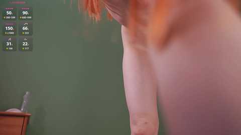 Video of a fair-skinned, topless woman with red hair, bending over, seen from the side. Background shows a green wall and a wooden table. Weather app with temperature (59\u00b0F) and humidity (66%) displayed.