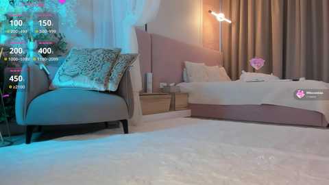 Media: Video of a minimalist, pastel-themed bedroom with a plush white carpet, a gray upholstered chair, and a bed with white linens and a pink headboard. A tall, modern lamp provides soft lighting.