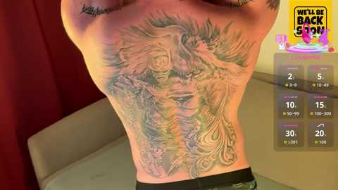 Video of a person's upper back tattoo featuring a detailed, realistic portrait of a woman in motion, surrounded by intricate floral designs. Background includes a red curtain and a yellow sign reading \"Well Back Shop.\