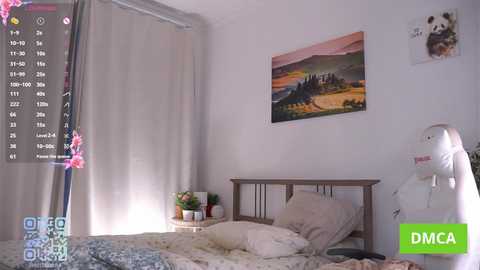Video of a minimalist, cozy bedroom with a wooden bed, beige curtains, and a framed landscape painting. A white teddy bear hangs on the wall.