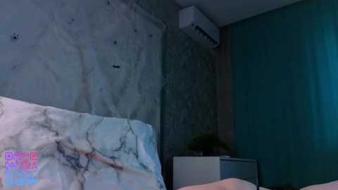 Video of a dimly lit room with a marble-patterned bedspread, a teal wall, a potted plant, and an air conditioner on the wall, creating a cool and modern ambiance.