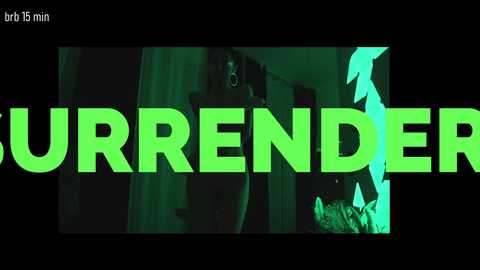 Media: A video of a woman in a dark room, wearing a mask, with neon green text overlaying the image, \"BRT 15 MIN\" and \"URRNDER.\
