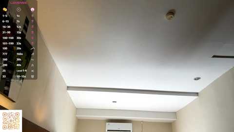 Video of a modern, minimalist ceiling with a recessed light, air conditioning unit, and a digital clock. The background shows beige walls and a wooden shelf on the left.