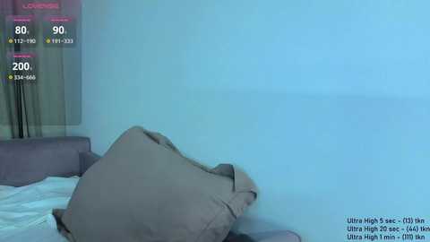 Video of a minimalist bedroom with a blue wall, a gray pillow, and a partially visible window with sheer curtains.