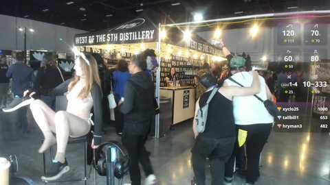 Media: Video of a crowded, dimly lit indoor event with a \"Whisky of the Year\" booth, attendees in casual attire, and a sign displaying time and temperature.