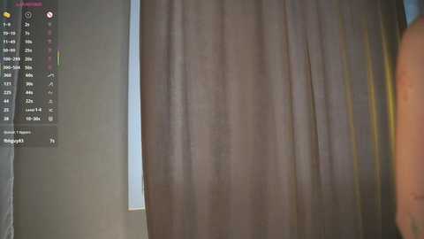 A video shows a beige curtain partially covering a window, with a digital display on the left listing time, date, and weather. The room's lighting is soft, and the background is out of focus.