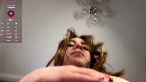 A low-angle video of a woman with long, brown hair, captured in a playful, dynamic pose, with a digital overlay of social media icons.