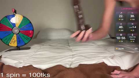 Video of a person on a bed, holding a brown object, with a colorful pinwheel and a fitness app display in the background.