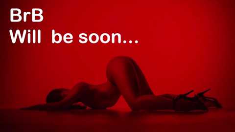 A video of a nude woman with fair skin and medium build, kneeling on all fours with her back arched, against a red background. She wears black high heels. Text reads, \"BrB Will be soon...\