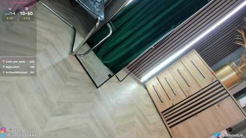 Video of a modern, dimly lit room with light wood flooring, green curtains, metallic furniture, and a wooden cabinet with horizontal drawers. The image is timestamped at 10:59:59.