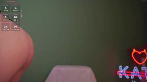 Video of a person's buttocks in a green room with a neon \"KAR\" sign and a digital clock displaying 3:10 PM.