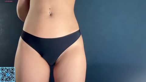 Media: Video of a woman's midsection, showcasing her light skin tone, navel piercing, and black bikini-style panties. The background is a dark blue gradient.