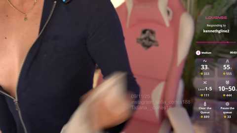A close-up video of a woman's partially unzipped navy blue top, revealing a black bra. Behind her is a pink backpack with a logo. The image is overlaid with a live streaming video feed, displaying a live chat and temperature reading.