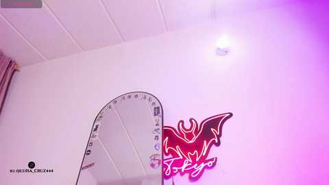 Video of a ceiling-mounted wall clock with a white face and black numbers, set against a white ceiling and purple-painted wall with a red, stylized dragon mural.