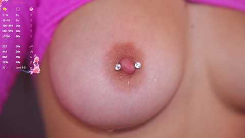 Video of a close-up view of a woman's large, pierced breast, featuring a nipple with a barbell and a pink areola. Her skin is light and smooth, and she's wearing a purple top.