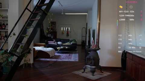 Video of a dimly-lit living room with a black metal spiral staircase, a black sofa, and a large flat-screen TV displaying a game interface. The background reveals a kitchen and hallway.