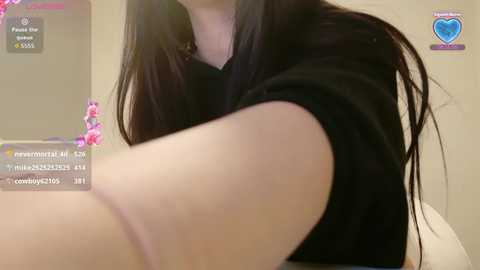 Media: A video of a woman with long black hair, wearing a black top, taken indoors with a bathroom setting. The image includes a live stream overlay with chat messages.