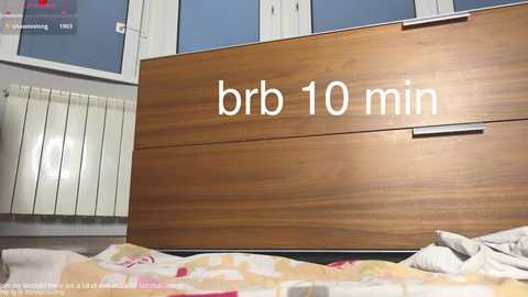Media: Video of a modern bedroom showing a wooden headboard with \"bbr 10 min\" written on it, a white radiator, and a colorful quilted bedspread.