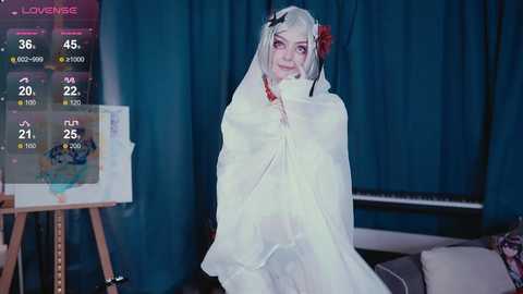 Video of a white woman with short, platinum hair in a bridal veil, holding a red flower, standing in front of a whiteboard with a love meter and text.