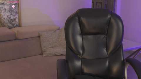 Video of a black leather office chair in a modern living room with beige sofa, textured pillows, framed artwork, and purple ambient lighting.