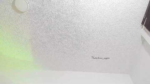 A video of a textured white ceiling with a circular light fixture, featuring a green lens flare on the left and a signature \"Nathan Langan\" at the bottom center.
