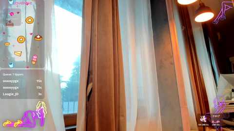 A video of a cozy room with a large window covered by sheer curtains, showing a sunny outdoor view. The room is warm with wooden furniture and soft lighting.