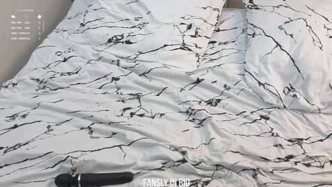 Video of a white bedsheet with a black marble pattern, slightly wrinkled, with a black dildo partially visible at the bottom left corner.