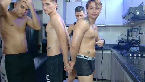Video of four shirtless Asian men in black underwear in a modern kitchen, holding hands, tattoos on forearms, smiling.