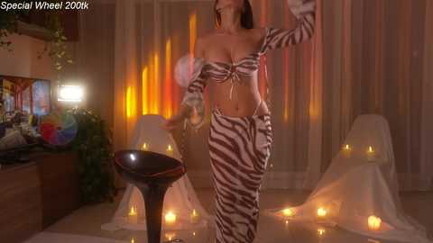 Video of a woman in a zebra-patterned outfit dancing energetically on a lit stage with a dark-haired man, surrounded by candles and vibrant orange lighting.