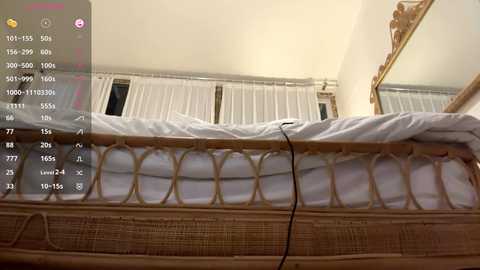 Video of a wooden bed with a white bedspread, white curtains, and a mirror. A smartphone screen displaying a video recording is overlaid in the top left corner.