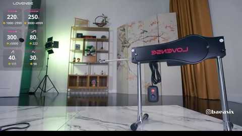 Video of a modern, minimalist room with a black tripod, a wooden shelf, and beige curtains. A white marble floor reflects the light.