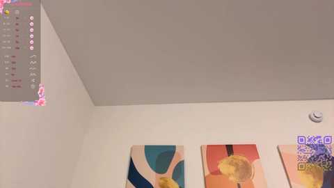 Media: Video of a minimalist, modern room with a white ceiling, beige walls, and three abstract artworks featuring geometric shapes and pastel colors.