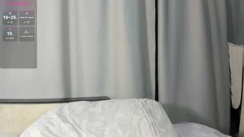 Video of a hospital room with a white patient bed, a light gray curtain, and a digital display showing 10:25 AM, with icons indicating \"vital signs\" and \"temperature.\