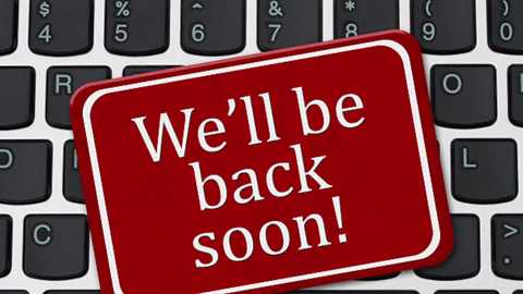 Video of a red sticker with white text reading \"We'll be back soon!\" placed on a black keyboard with white keys. The sticker is centrally positioned, creating a contrast against the keyboard's surface.