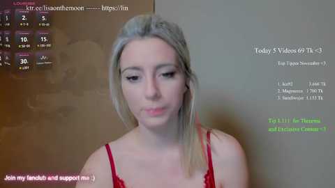 A video of a fair-skinned, blonde woman in a red lace bra, with a computer screen showing a chat window.