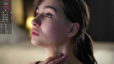 Video of a young woman with fair skin and brown hair, looking contemplative. Background is blurred, possibly an indoor setting.