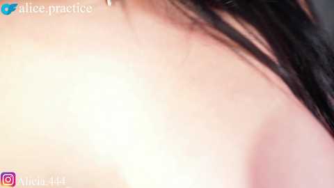 A close-up video of a woman's bare shoulder with smooth, fair skin and long, dark hair. The image has a soft focus, highlighting the natural texture of her skin.