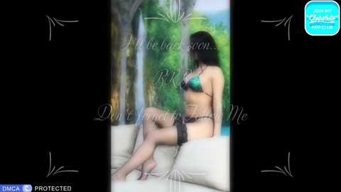 Video of a dark-haired woman in a green bikini, sitting on a beige sofa in a lush green room.