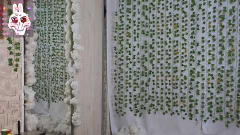 Video of a room with a white wall covered in densely packed, green potted plants, creating a lush, vertical garden effect. The plants are interspersed with fluffy white faux snow, adding a whimsical, winter-themed touch.